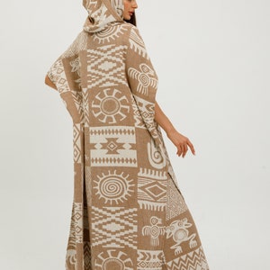 May include: A long, brown hooded poncho with a white geometric pattern. The poncho has a fringed hem and is made of a soft, woven fabric.