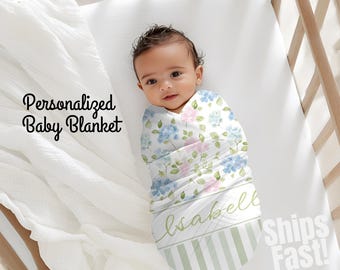 May include: A baby wrapped in a floral-patterned blanket with blue and pink flowers. The blanket is personalized with a name and has a green and white striped border. The text "Personalized Baby Blanket" is visible.