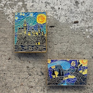 May include: Two enamel pins featuring a stylized version of Vincent van Gogh's Starry Night. The first pin depicts Hogwarts Castle, while the second pin shows three figures walking along a path.