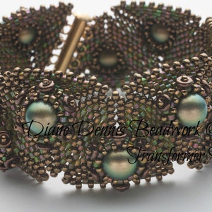 May include: A close-up of a brown and green beaded bracelet with a gold clasp. The bracelet is made with small seed beads and larger iridescent beads. The text "Diane Dennis Beadwork © 2014 Transformer Bracelet" is visible on the bracelet.