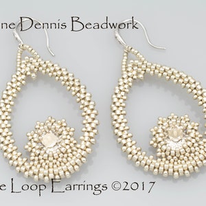 May include: A pair of silver beaded earrings with a teardrop shape. The earrings feature a small crystal bead in the center of each teardrop. The earrings are labeled "In the Loop Earrings ©2017".