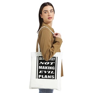 Puede incluir: Bolsa de tela blanca con texto negro que dice "Definitely Not Making Evil Plans".