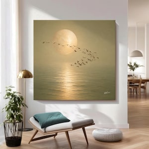 Könnte beinhalten: Ein quadratisches Wandbild, das einen großen, blassgelben Mond über einem ruhigen, spiegelnden Meer zeigt. Ein Schwarm dunkler Vögel fliegt in einer geschwungenen Formation vor dem Mond und dem dunstigen, goldfarbenen Horizont. Eine Signatur ist zu sehen.