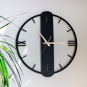 May include: A black and white clock with Roman numeral markings. The clock has a black frame and a white face. The hands are gold.