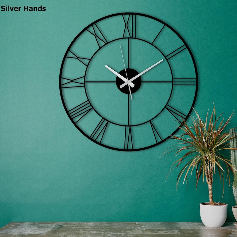 May include: A black metal clock with Roman numeral markings on a teal wall. The clock has silver hands and a black center.