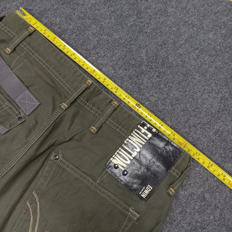 Op de afbeelding: Groene cargo broek met meerdere zakken en een zwart lederen patch met de tekst "E-FUNCTION EDWIN".