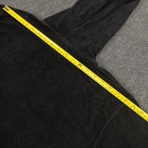Puede incluir: Una camisa negra de manga larga con una cinta m&eacute;trica amarilla colocada sobre ella. La cinta mide 50,8 cm.