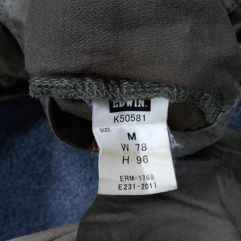 May include: A brown clothing tag with white text that reads "EDWIN. K50581 SIZE M W 78 H 96 ERM-1769 E231-2011"