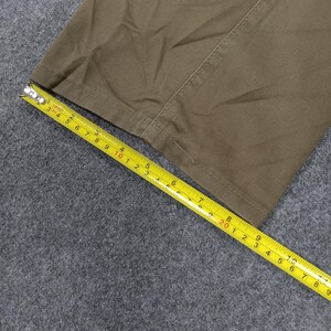 May include: Close-up of a brown fabric with a seam running down the center. A yellow measuring tape is laid across the fabric, showing measurements in inches.