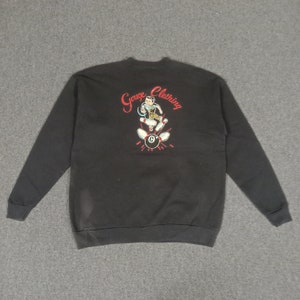 May include: Black sweatshirt with a red and white graphic of a cartoon man bowling. The graphic includes the text "Gauge Clothing".