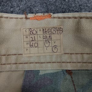 May include: A brown paper tag with handwritten measurements in inches and centimeters. The tag reads: "C 80 A 165 255  N 21 L 42.5 W 60 G V P E D"