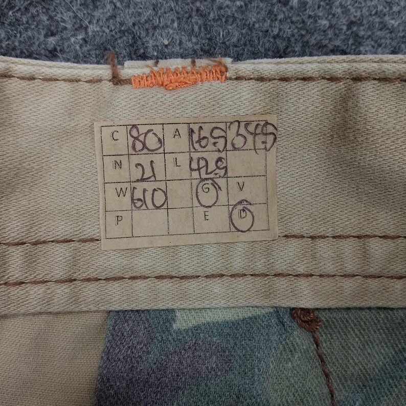 May include: A brown paper tag with handwritten measurements in inches and centimeters. The tag reads: "C 80 A 165 255  N 21 L 42.5 W 60 G V P E D"