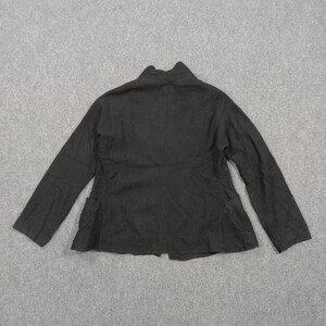 May include: A solid black long-sleeved jacket featuring a high collar, a central vertical seam down the back, and two patch pockets positioned at the lower front sides. The garment is constructed with a straight hemline and long sleeves.