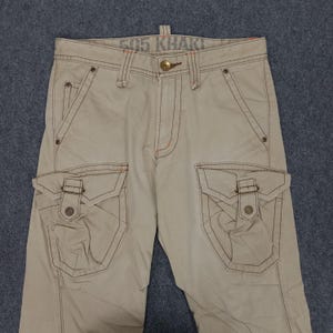 May include: Beige cargo pants with multiple pockets and a contrasting stitch detail. The pants have the text "505 Khaki" printed on the waistband.
