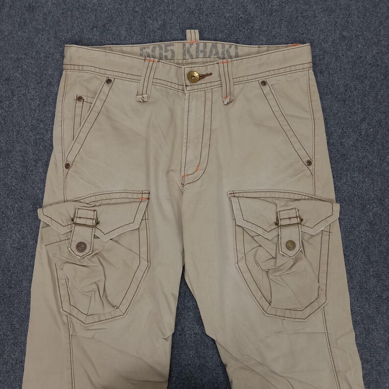 May include: Beige cargo pants with multiple pockets and a contrasting stitch detail. The pants have the text "505 Khaki" printed on the waistband.
