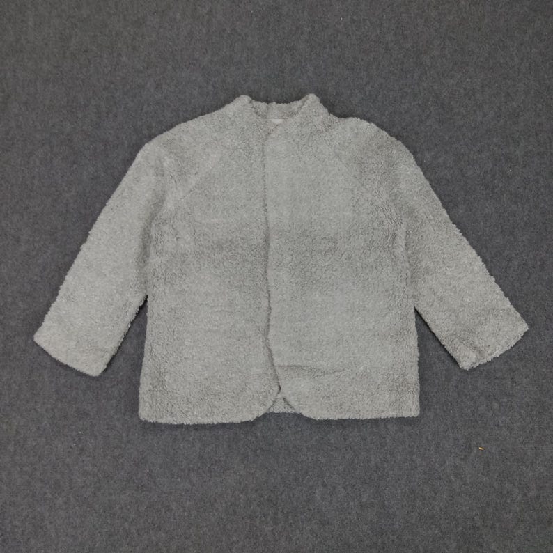 Op de afbeelding: Een grijze, pluche cardigan met lange mouwen en een knoopsluiting aan de voorkant.