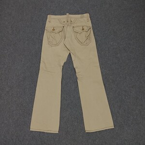 May include: A pair of beige, straight-leg pants with two large pockets on the back. The pockets have a decorative stitching detail.