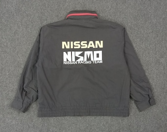 May include: A dark gray jacket with a red-trimmed collar. The back of the jacket features the white text "NISSAN NISMO NISSAN RACING TEAM". The jacket has long sleeves and a zipper closure.