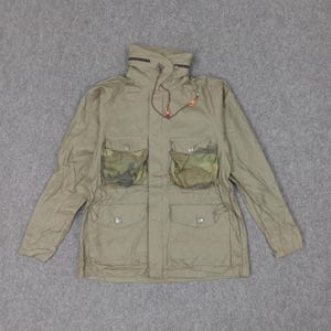 May include: Olive green jacket with a high collar and multiple pockets. The two chest pockets feature a camouflage pattern. The jacket has a drawstring at the collar and a zipper closure. The jacket is made of a lightweight material.