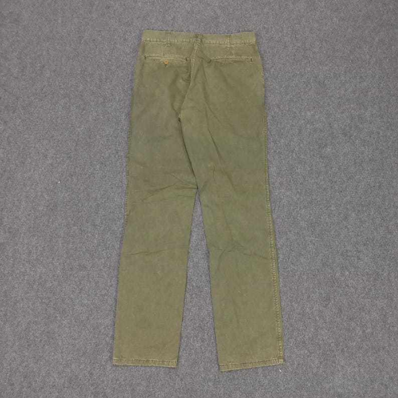 May include: A pair of olive green trousers with a button fly and belt loops.