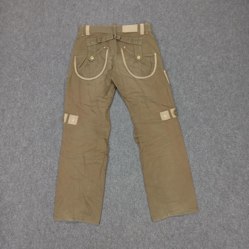 May include: Brown cargo pants with beige trim and multiple pockets. The pants have a belt loop and a button closure.