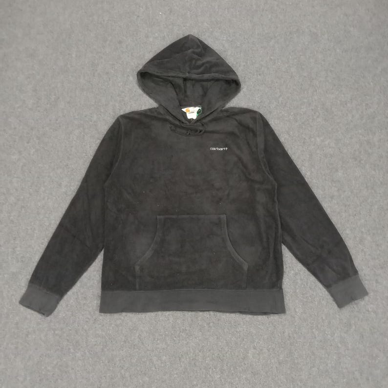 Puede incluir: Sudadera con capucha negra con un bolsillo frontal y la palabra "Carhartt" bordada en el pecho.