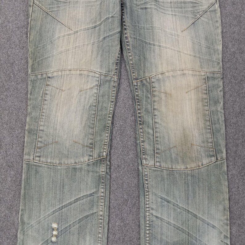 May include: Light blue denim jeans with a faded wash and patchwork design. The jeans feature reinforced knee panels and decorative stitching. The denim has a worn appearance.