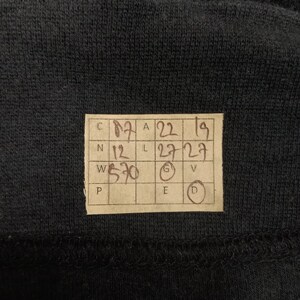 Puede incluir: Una etiqueta de papel marr&oacute;n con medidas de talla escritas a mano en pulgadas y cent&iacute;metros. La etiqueta tiene las letras C, N, W y P en la esquina superior izquierda, y las letras A, L, G, E y D en la esquina superior derecha. La etiqueta muestra las siguientes medidas: C 17, N 12, W 5'10, A 22, L 27, G 5, E 6, D 7.