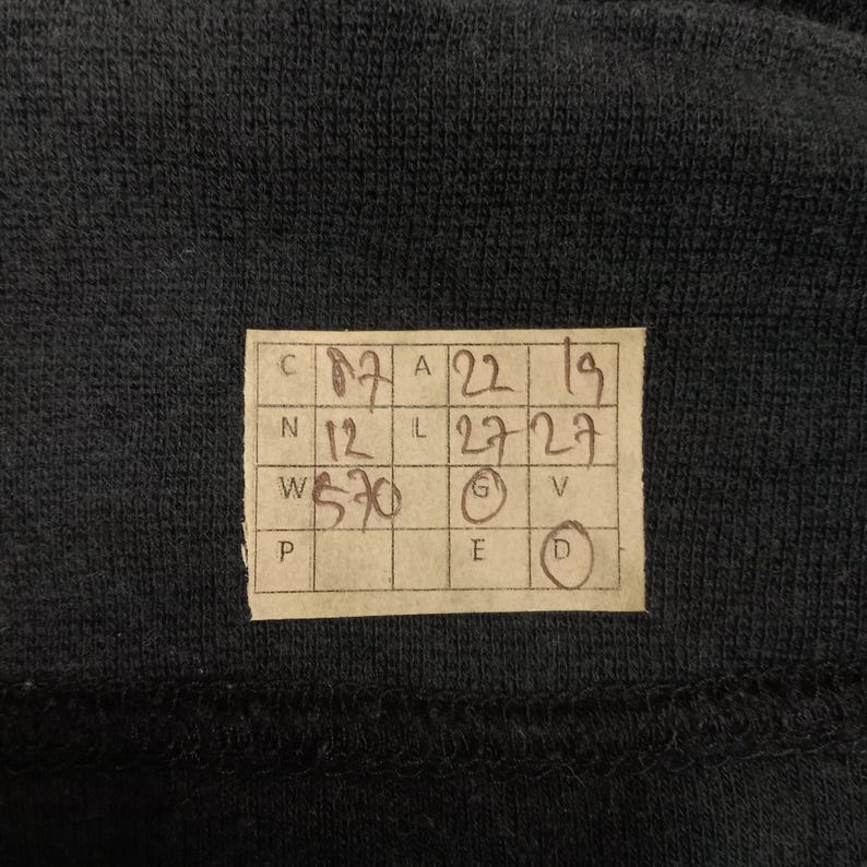 Puede incluir: Una etiqueta de papel marr&oacute;n con medidas de talla escritas a mano en pulgadas y cent&iacute;metros. La etiqueta tiene las letras C, N, W y P en la esquina superior izquierda, y las letras A, L, G, E y D en la esquina superior derecha. La etiqueta muestra las siguientes medidas: C 17, N 12, W 5'10, A 22, L 27, G 5, E 6, D 7.
