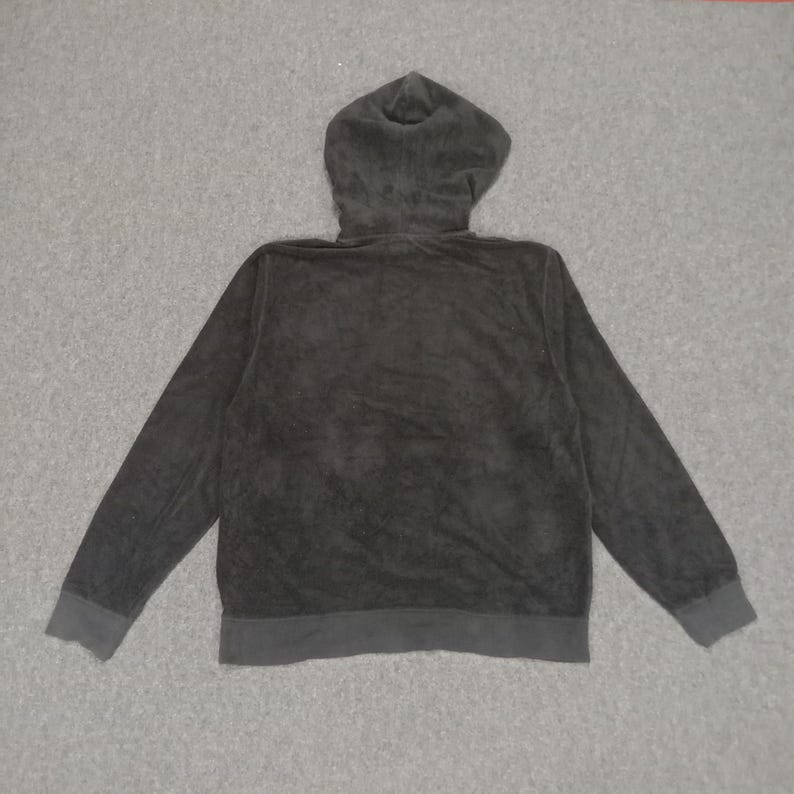 Puede incluir: Una sudadera con capucha negra con cierre de cremallera. La sudadera est&aacute; hecha de una tela suave y texturizada.