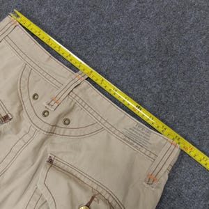 May include: Beige cargo pants with brown stitching and a label that reads "TYPE-505 THE CUTTING EDGE"