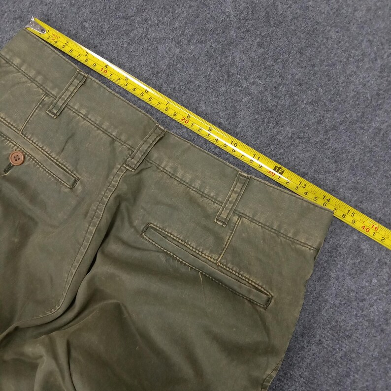 May include: A pair of olive green cargo trousers with a single back pocket. The trousers are made of a thick, durable fabric and have a relaxed fit.