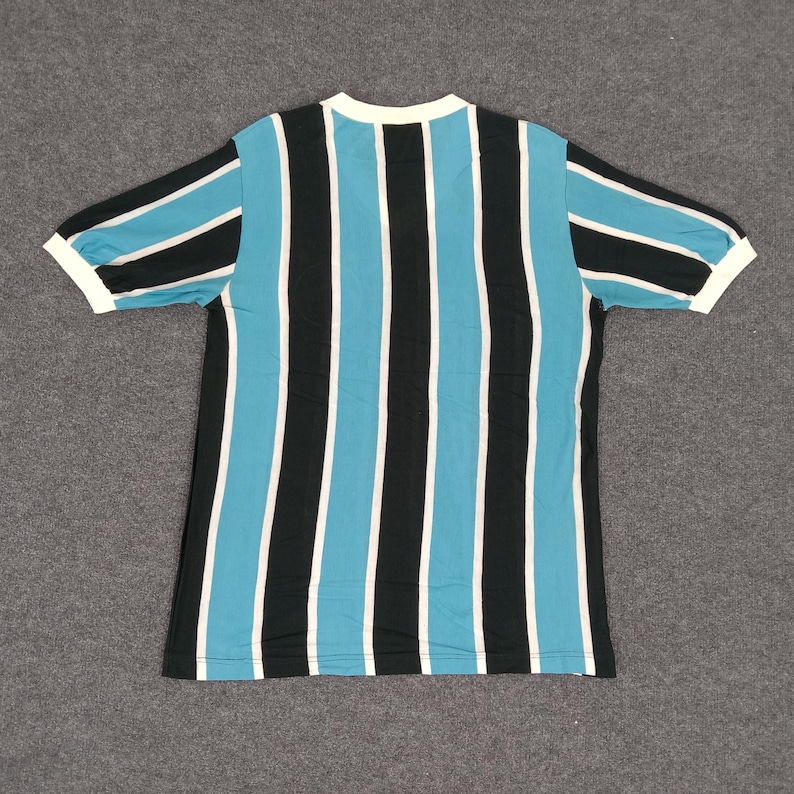 May include: A striped short-sleeved shirt with blue and black vertical stripes. The shirt has a white collar and white trim on the sleeves.