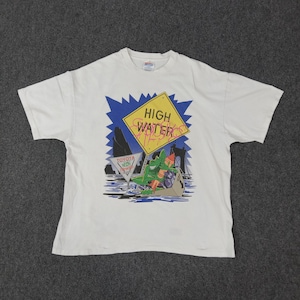 May include: White t-shirt featuring a cartoon alligator in a boat, with a "High Water" sign and the text "Toyota Week". The design includes blue, yellow, green, and red accents. The shirt is made of a soft, comfortable material.