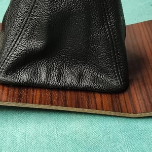 Könnte beinhalten: Eine braune Holzmaserung-Verkleidung für das Autoinnere mit einem schwarzen Leder-Schalthebel-Balg.