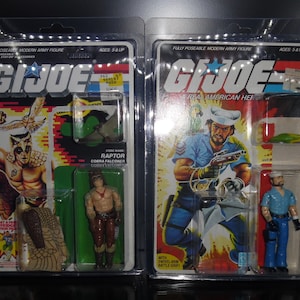 May include: Two vintage G.I. Joe action figure packages. The left package features a Cobra Falconer named Raptor with a brown and tan hawk. The right package features a Real American Hero with a blue and white sailor uniform and a parrot.