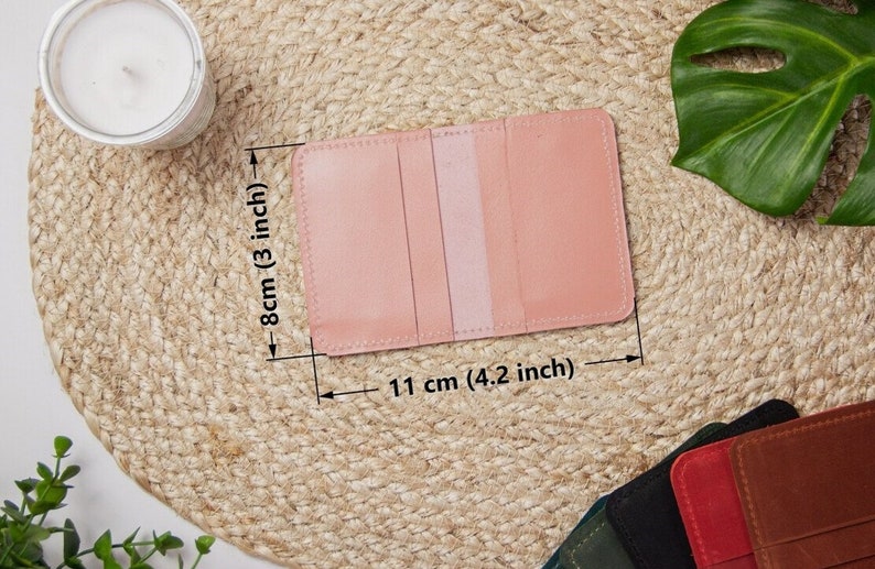 May include: A light pink leather card holder with three slots. The card holder measures 4.2 inches wide and 3 inches tall.