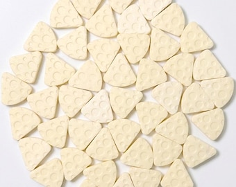 May include: A collection of light yellow, cheese-shaped objects with circular indentations, arranged in a circular pattern against a white background. The objects are all the same size and shape, resembling small cheese wedges.