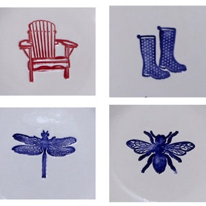 May include: Four ceramic tiles with different designs. The top left tile features a red Adirondack chair. The top right tile features two blue rain boots. The bottom left tile features a blue dragonfly. The bottom right tile features a blue bee.