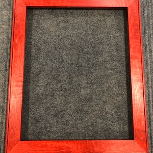 Puede incluir: Un marco de fotos de madera rojo con un diseño sencillo.