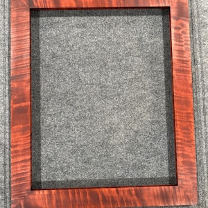 Pode incluir: Uma moldura de madeira para fotos com uma cor rica, marrom avermelhada. A moldura tem um design simples, retangular e um acabamento liso.