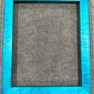 May include: A teal blue wooden picture frame with a smooth, polished finish. The frame is made of solid wood and has a simple, elegant design.