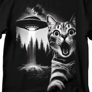 May include: A black and white illustration of a cat with a surprised expression, looking up at a UFO flying over a forest. The cat's mouth is open and its eyes are wide.