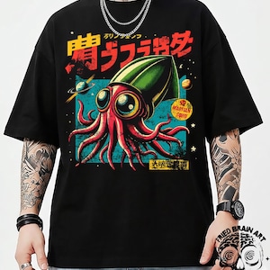 Op de afbeelding: Zwart T-shirt met een kleurrijke illustratie van een rood, octopusachtig wezen met een groene kop en grote ogen. Het ontwerp bevat Japanse tekst en de woorden "Martian Squid" op een gele cirkel. Het shirt heeft een relaxte pasvorm.