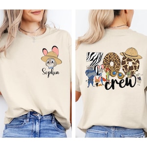 Puede incluir: Camiseta beige con un conejo de dibujos animados con sombrero de safari y el nombre "Sophia". La parte trasera de la camiseta muestra "Zoo Crew" con n&uacute;meros con estampado animal y personajes de dibujos animados.