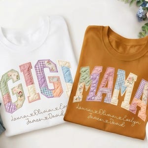 May include: Two crew neck t-shirts, one white and one yam-coloured, with the words "GIGI" and "MAMA" appliquéd in a patchwork design. The names "Laurare, Olivia, Evelyn, James, and David" are embroidered below the text.