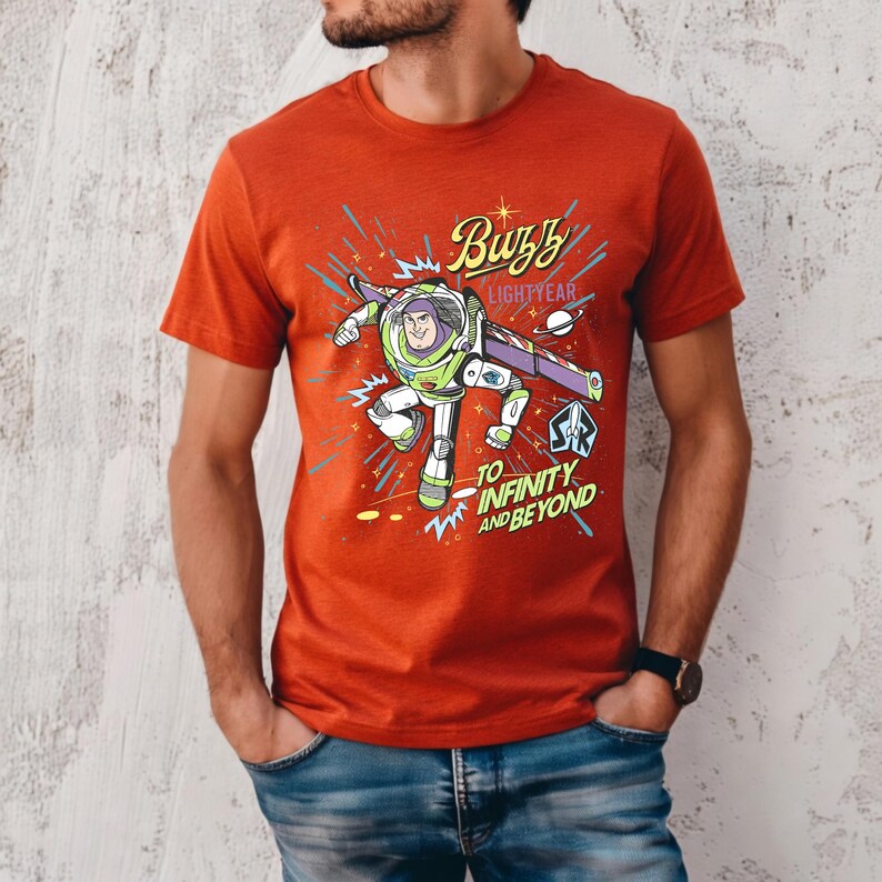 May include: A red t-shirt featuring a graphic of Buzz Lightyear from Toy Story. The design includes the text "Buzz Lightyear" and "To Infinity and Beyond" with a cartoon image of the character in action. The shirt is short-sleeved.