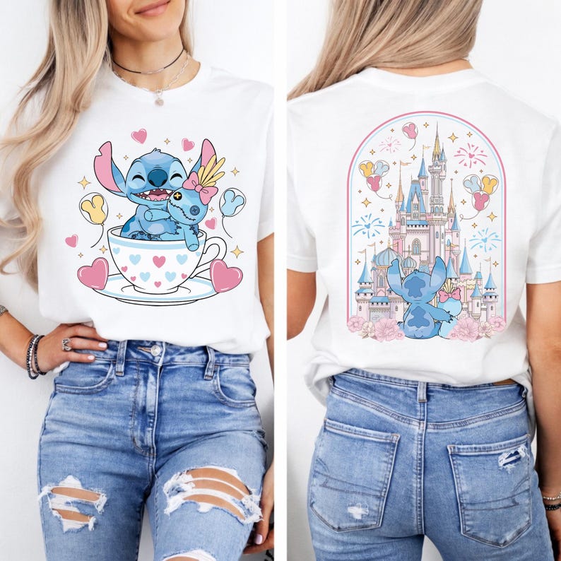 May include: White t-shirt featuring a cartoon image of a blue alien character in a teacup with a doll, surrounded by hearts and balloons. The back of the shirt shows a castle with the same character. The shirt is paired with blue jeans.