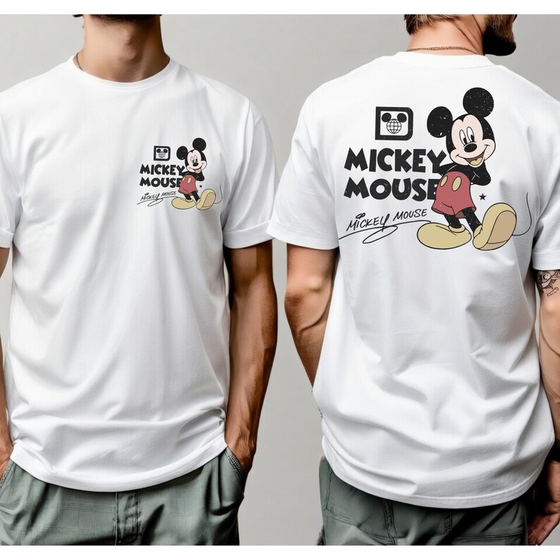 May include: White t-shirt featuring a Mickey Mouse graphic on the front and back. The front graphic is smaller, while the back graphic is larger. The design includes Mickey Mouse in his classic outfit, with the words "Mickey Mouse" and "Mickey Mouse" in a stylized font.
