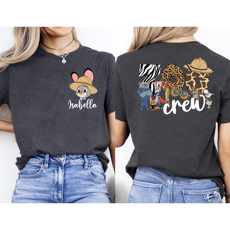 Puede incluir: Camiseta gris oscuro con un personaje de dibujos animados con sombrero de safari y el nombre "Isabella". La parte trasera de la camiseta muestra "Zoo Crew" con letras con estampado animal y varios personajes de dibujos animados.